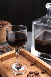 Photo of Coffee liqueur and beans on grey table, closeup