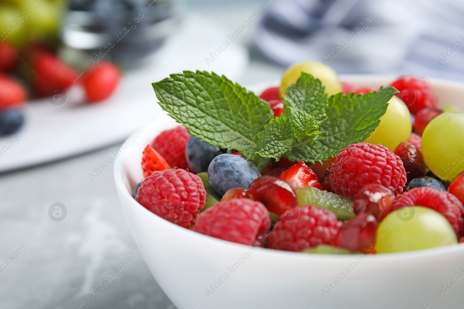 Photo of Fresh tasty fruit salad on grey marble table, closeup