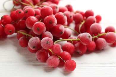 Tasty frozen red currants on white wooden table, closeup