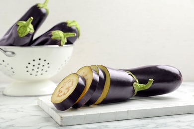 Photo of Wooden board with ripe eggplants on table