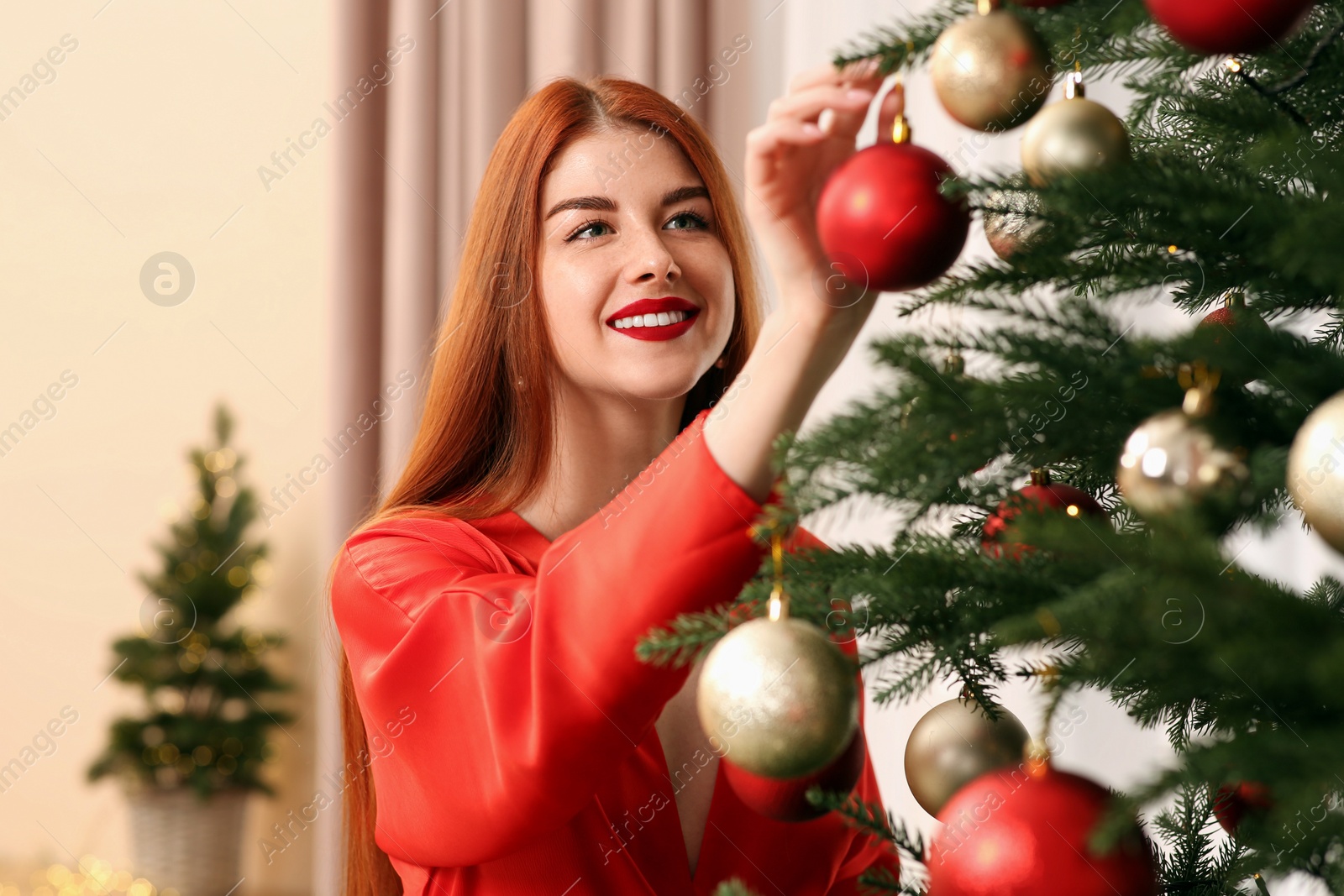 Photo of Beautiful young woman decorating Christmas tree at home