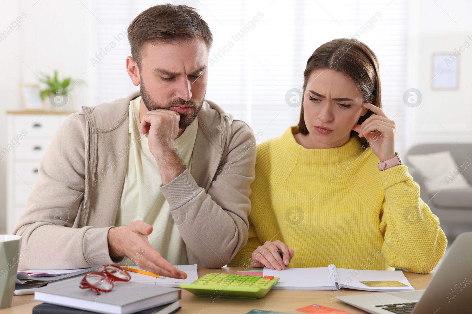 Photo of Young couple discussing family budget at table in living room