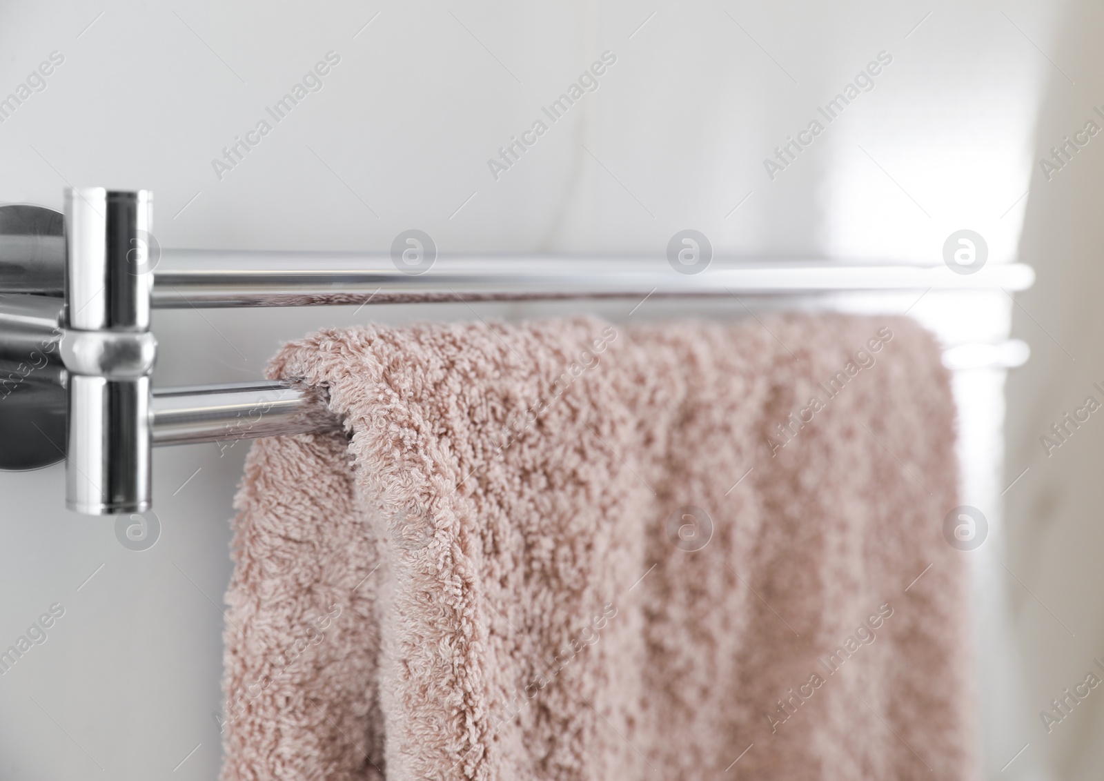 Photo of Holder with clean towel on light wall in bathroom, closeup