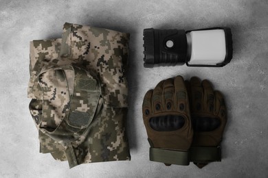 Photo of Tactical gloves, camouflage jacket and camping lantern on light gray background, flat lay. Military training equipment