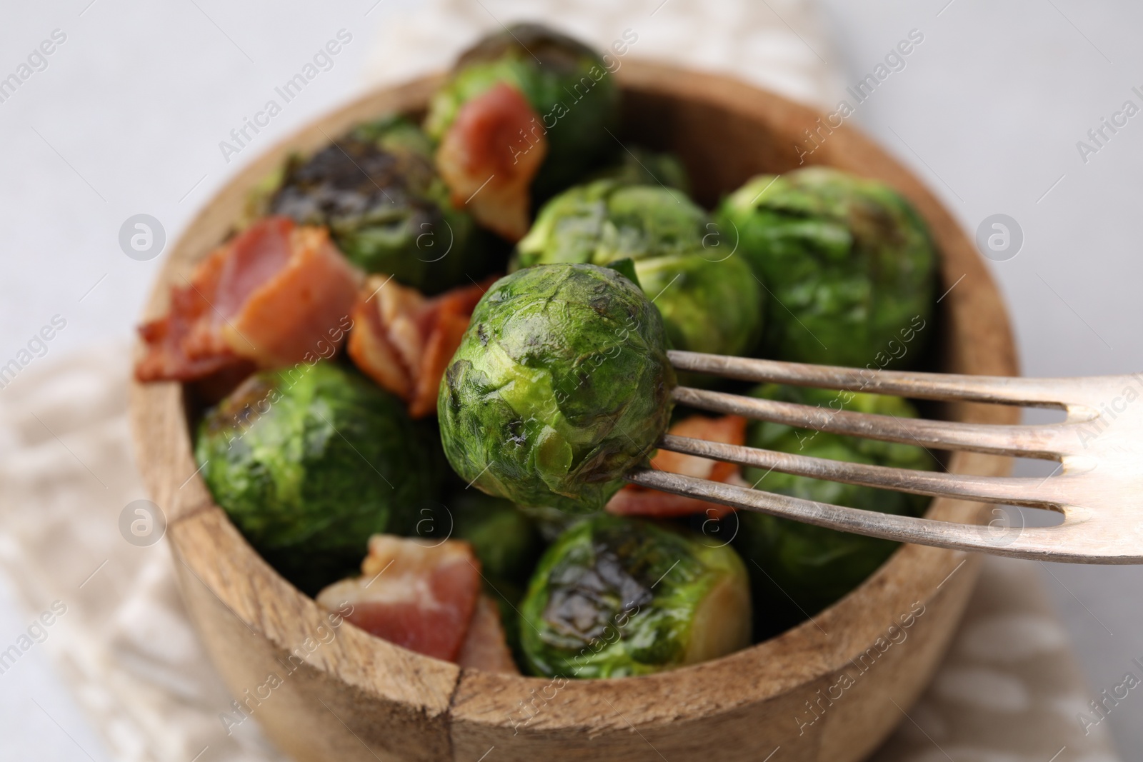 Photo of Eating delicious roasted Brussels sprouts at table, closeup