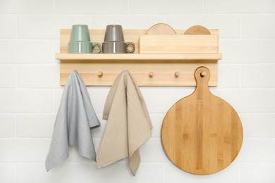 Photo of Different towels and wooden board hanging on rack in kitchen
