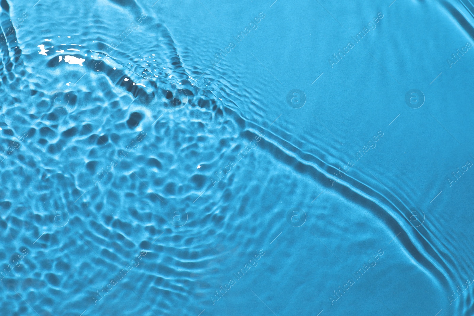 Image of Rippled surface of clear water on light blue background, closeup