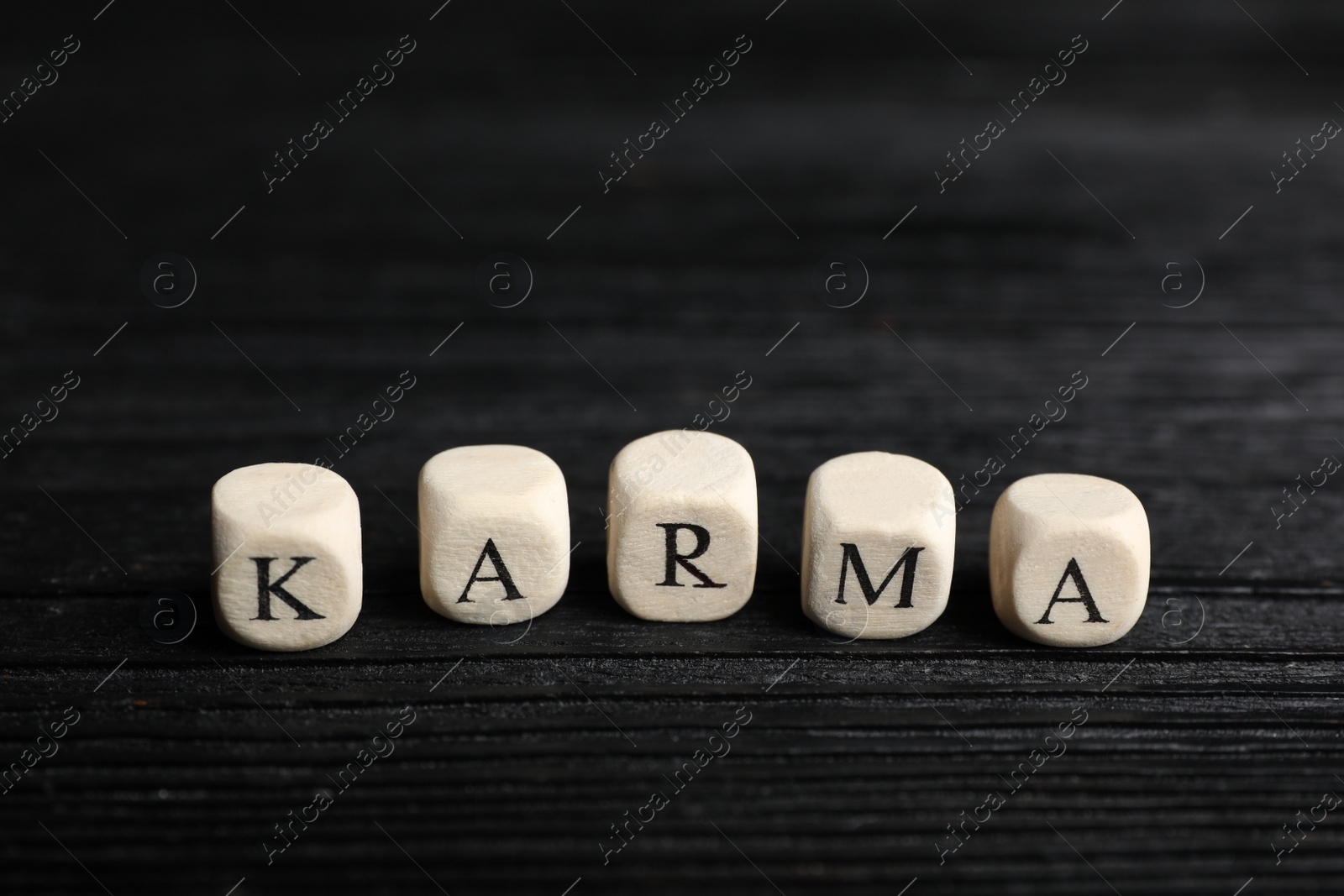 Photo of Word Karma made of cubes with letters on black wooden table