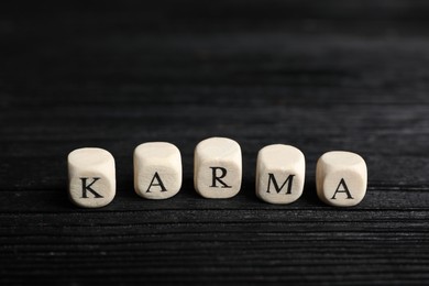 Photo of Word Karma made of cubes with letters on black wooden table