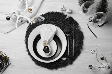 Photo of Festive table setting with bunny ears made of black egg and napkin, flat lay. Easter celebration