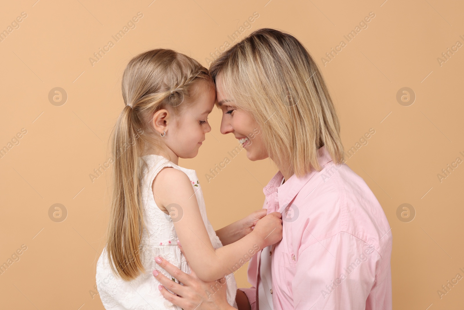 Photo of Family portrait of happy mother and daughter on beige background