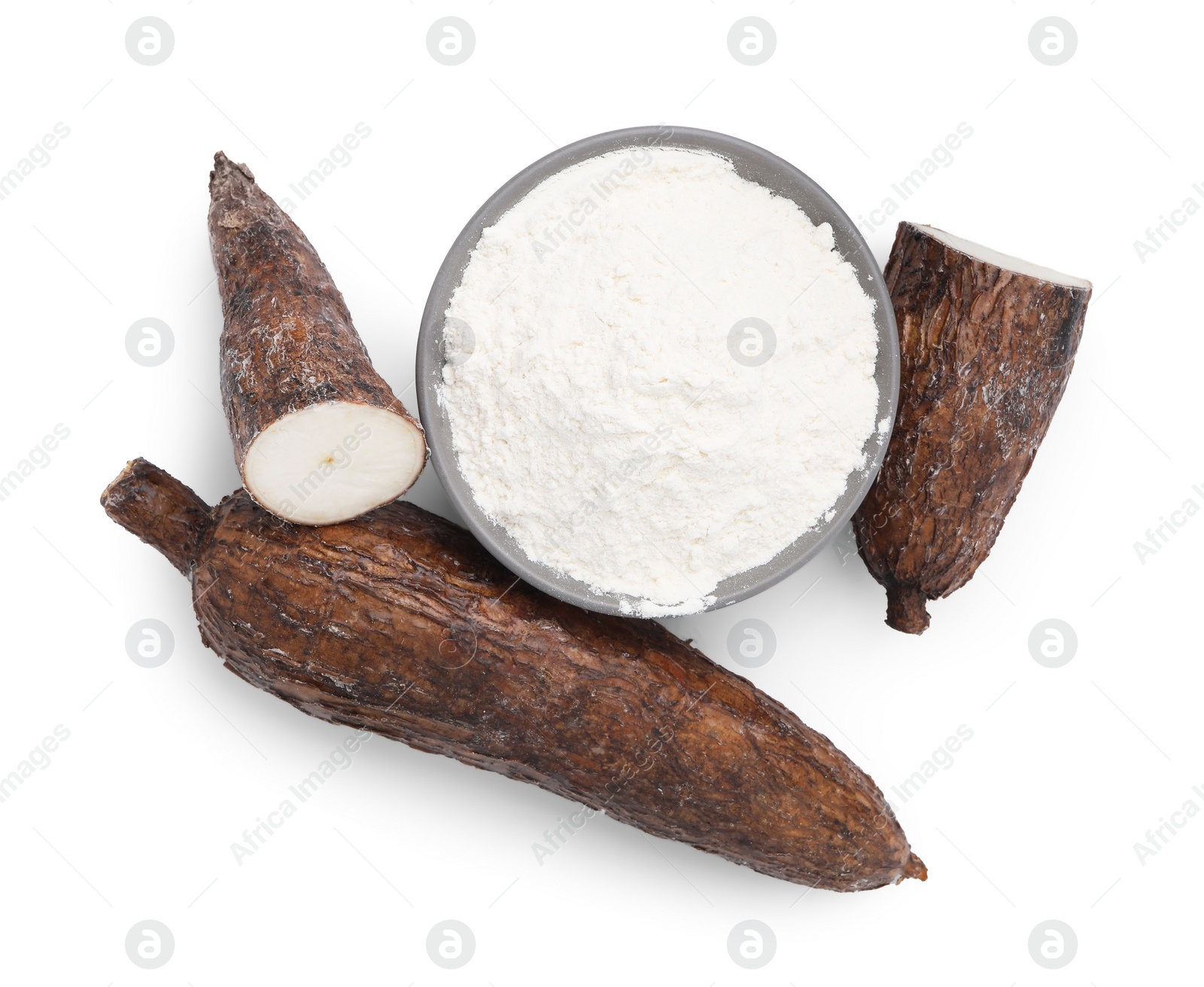 Photo of Bowl with cassava flour and roots isolated on white, top view