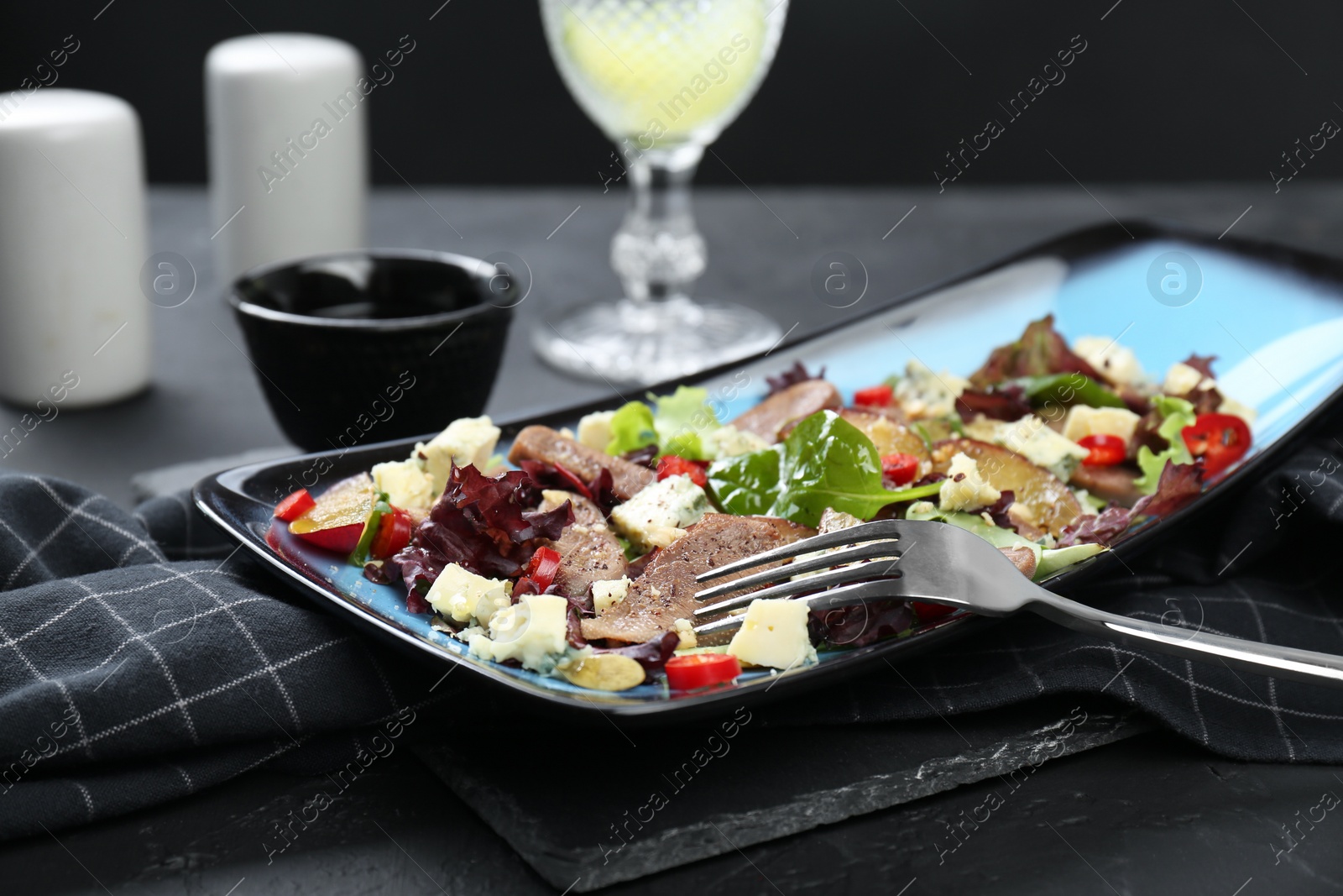 Photo of Delicious salad with beef tongue, cheese and fork served on black table, closeup