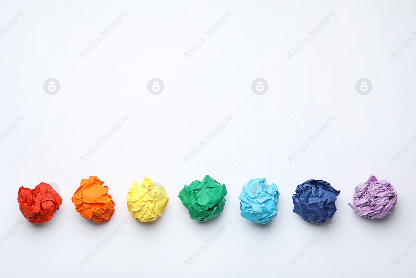 Photo of Colorful crumpled sheets of paper on white background, top view