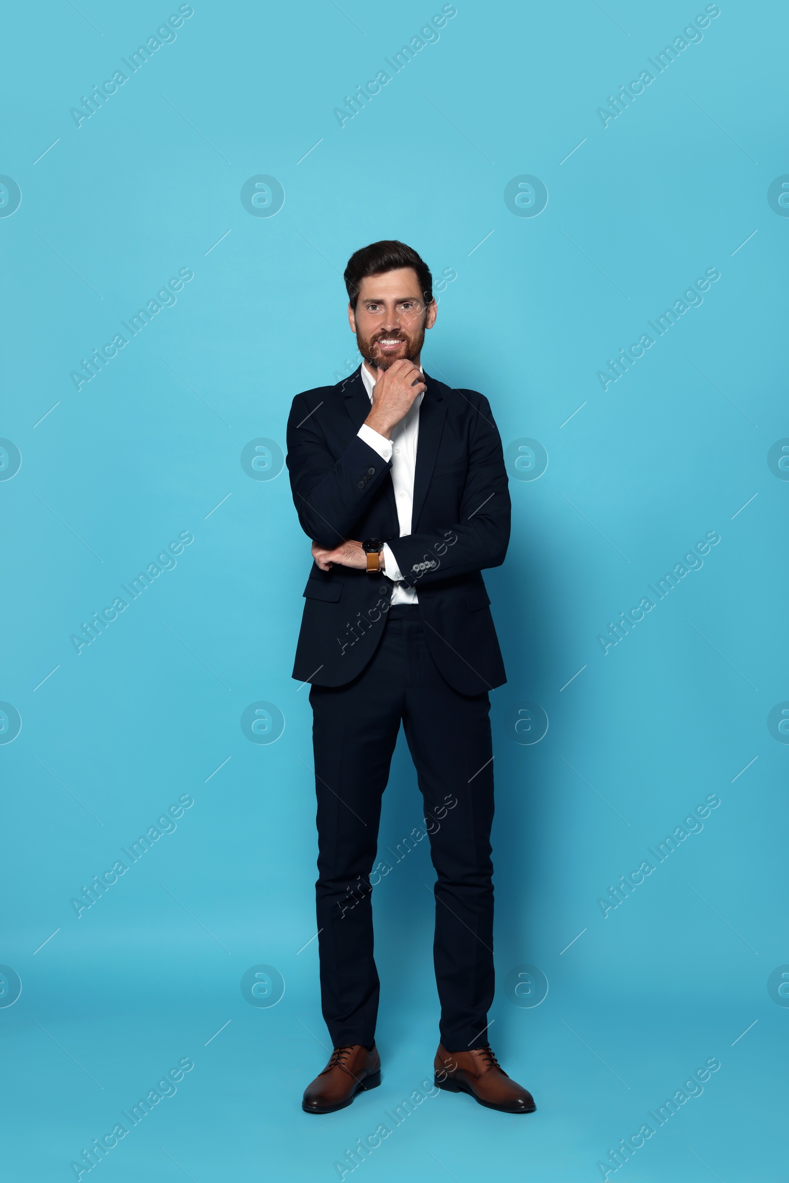 Photo of Smiling bearded man in suit on light blue background