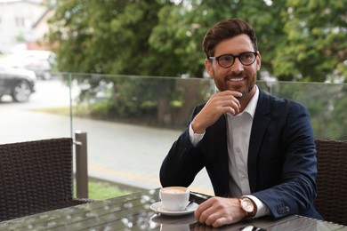 Smiling handsome bearded man with coffee in cafe. Space for text