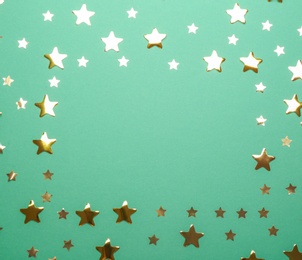 Photo of Frame made of confetti stars with space for text on green background, top view. Christmas celebration