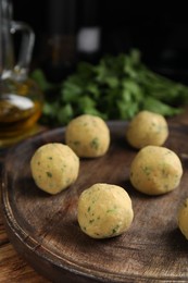 Wooden board with raw falafel balls on table, closeup