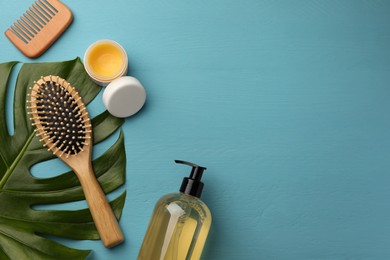 Photo of Hair brush, comb, shampoo and balm on light blue wooden table, flat lay. Space for text