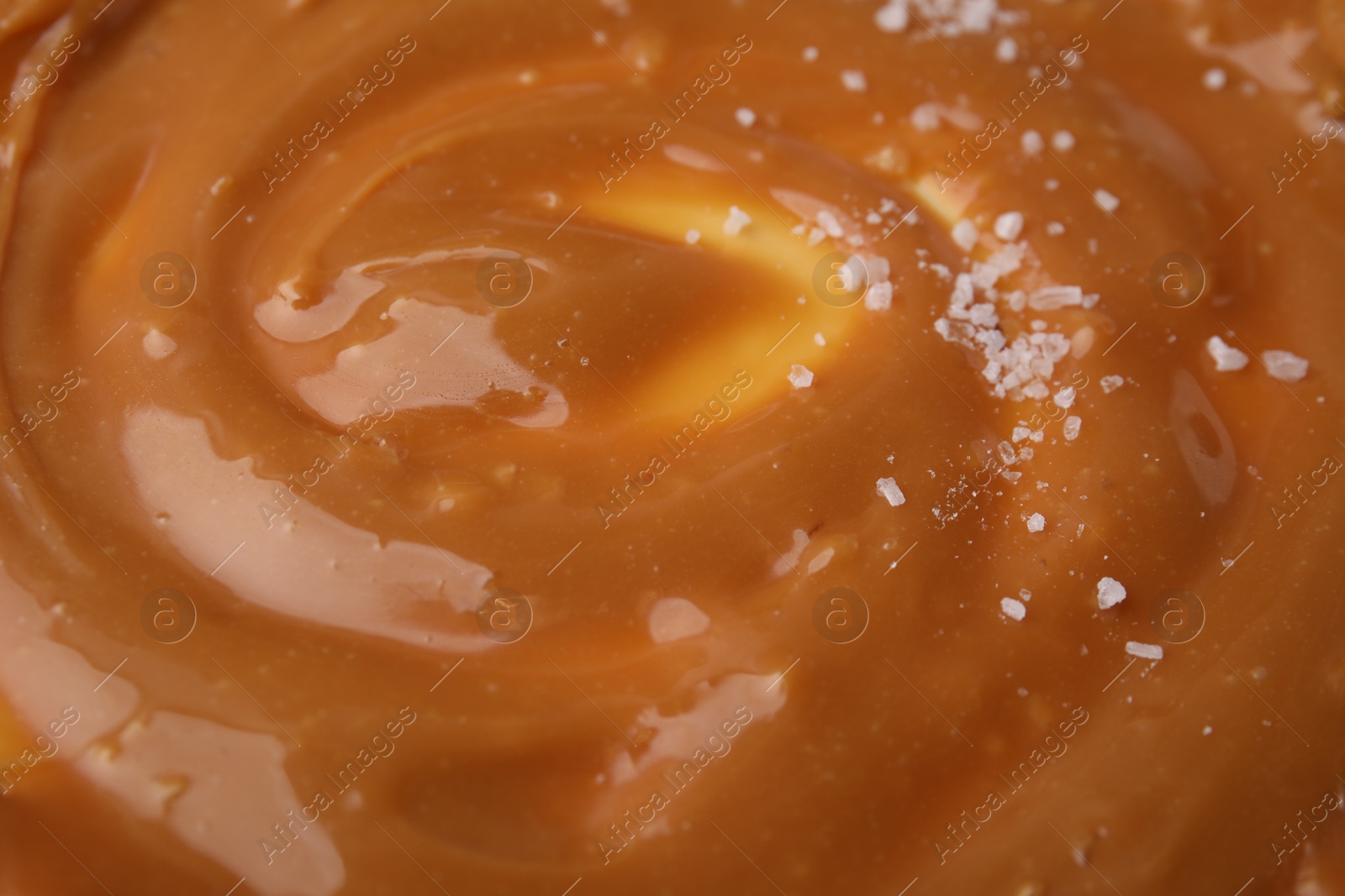 Photo of Delicious caramel sauce with sea salt as background, closeup