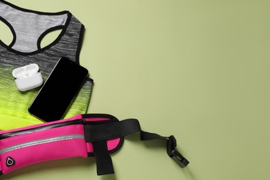 Photo of Flat lay composition with stylish pink waist bag on pale green background. Space for text