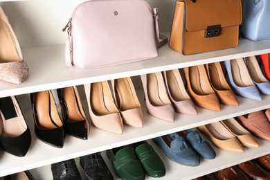 Photo of White shelving unit with different leather shoes and bags
