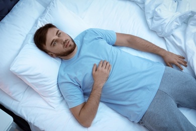 Photo of Young man lying in bed at night. Sleep disorder