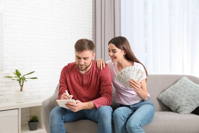 Beautiful young couple with money at home