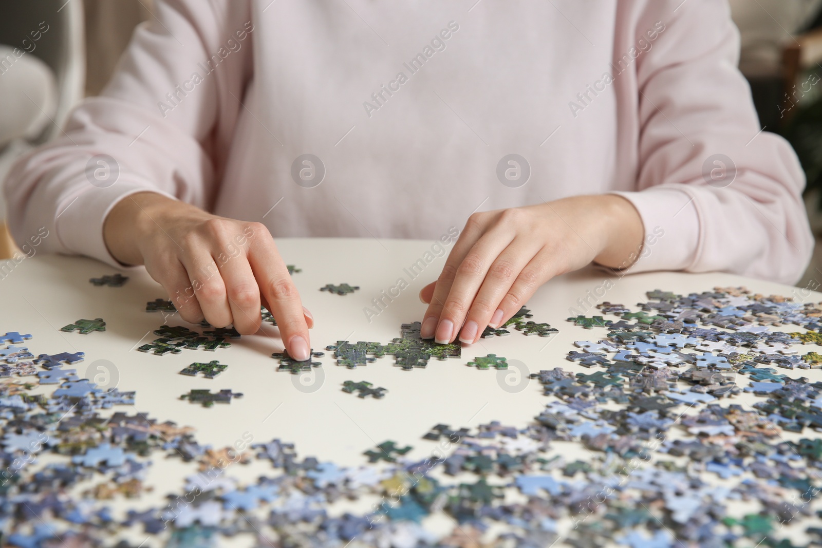 Photo of Young woman playing with puzzles at table, closeup