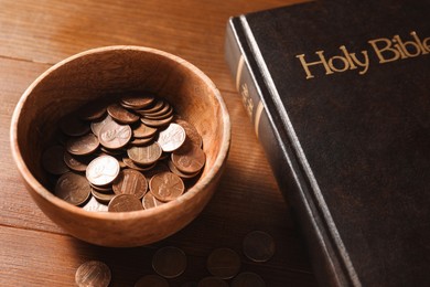 Donate and give concept. Coins in bowl and Bible on wooden table