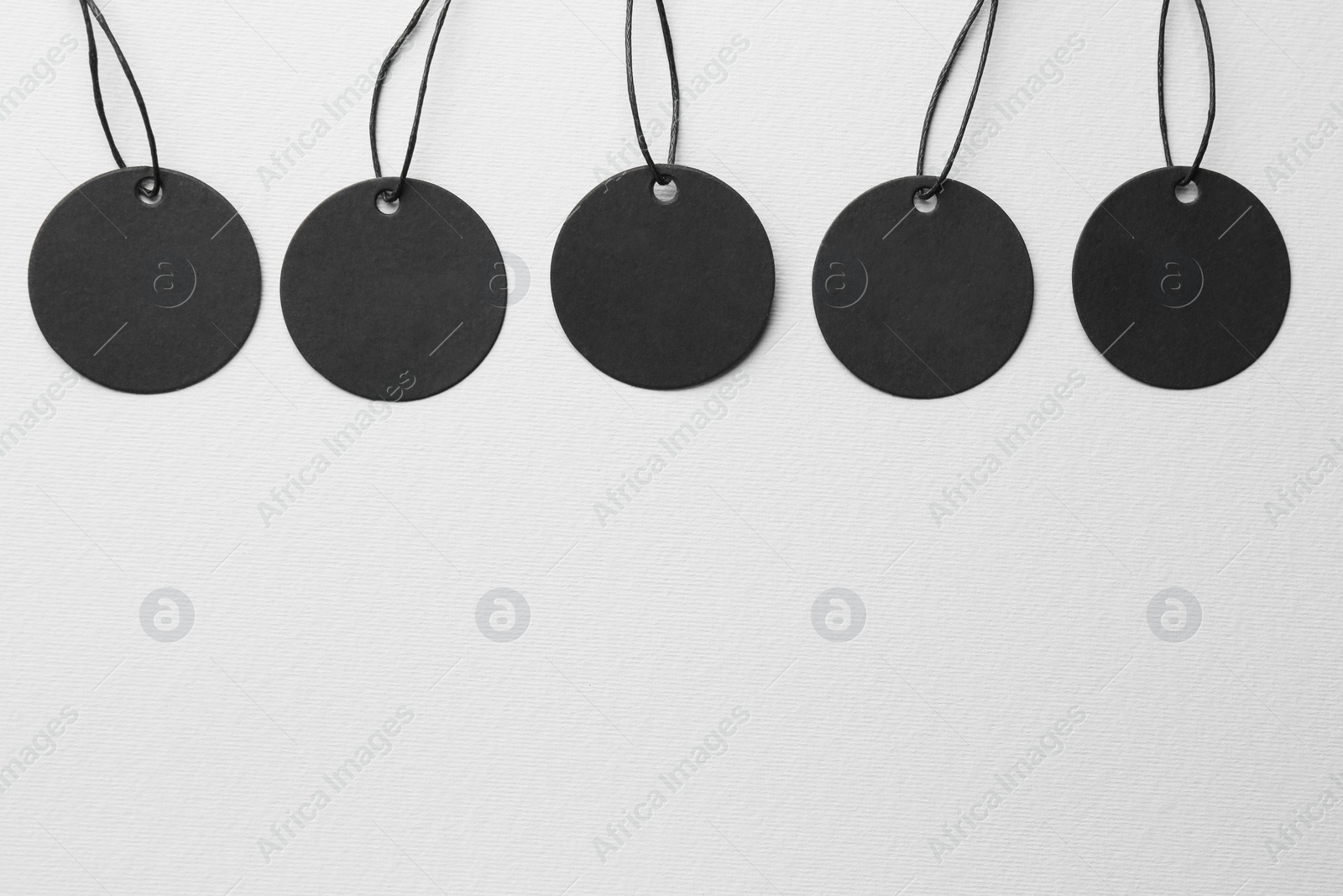 Photo of Set of circle shaped tags with space for text on light grey background, flat lay