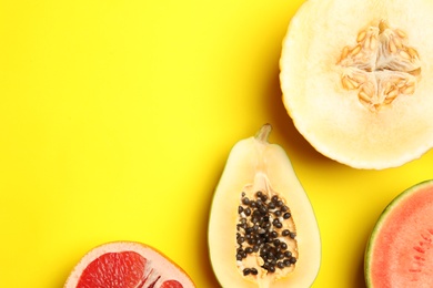 Photo of Flat lay composition with tasty melon and fresh tropical fruits on yellow background, space for text