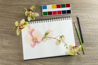 Flat lay composition with beautiful drawing of orchid
flowers on wooden table