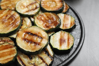 Photo of Delicious grilled zucchini slices served on grey table, closeup