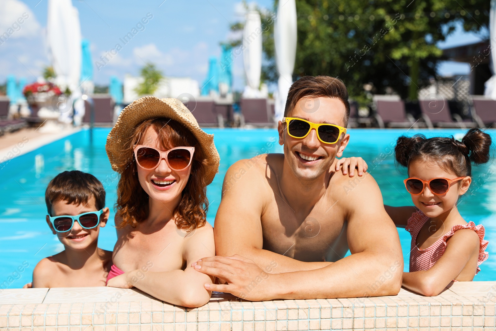 Photo of Happy family in swimming pool at resort