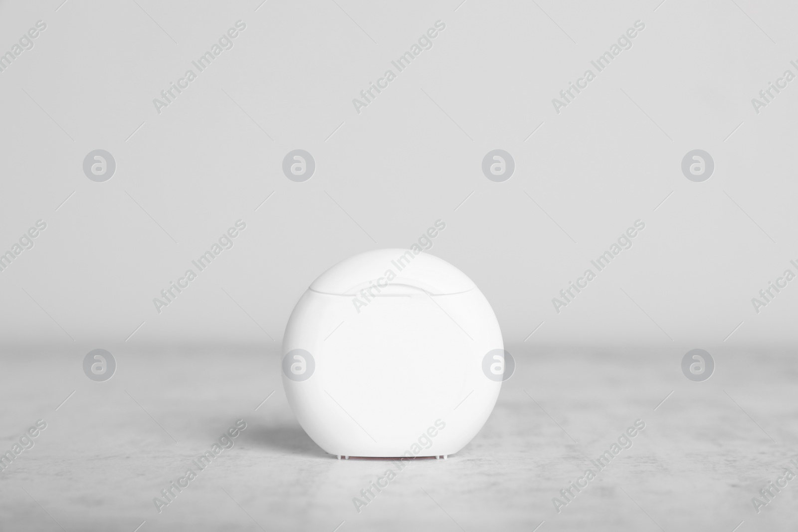 Photo of Container with dental floss on light grey textured table