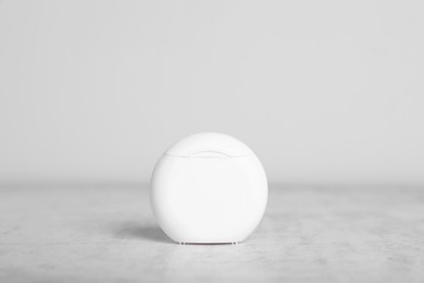 Container with dental floss on light grey textured table