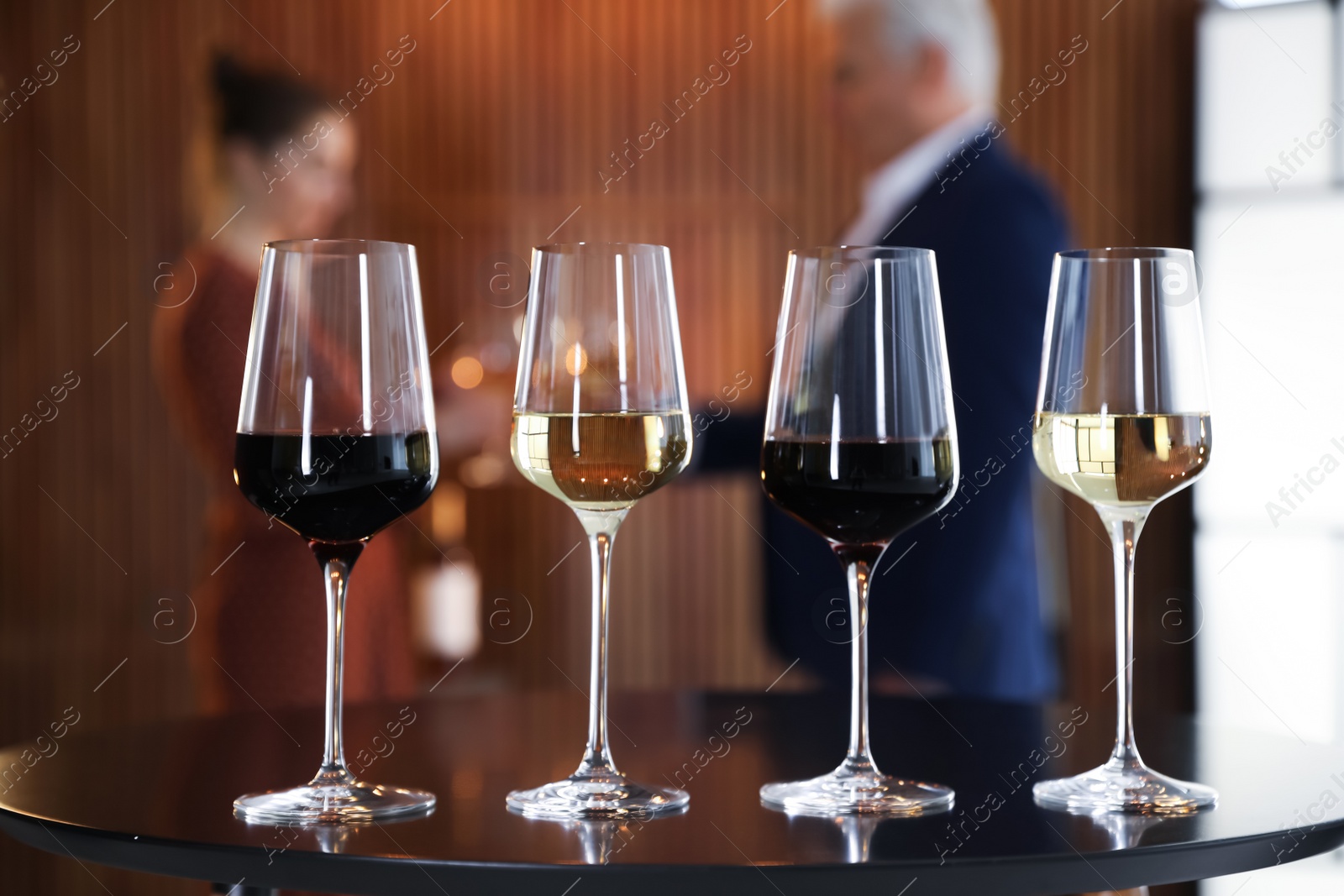 Photo of Glasses of different wines on table against blurred background