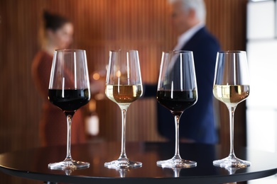 Photo of Glasses of different wines on table against blurred background