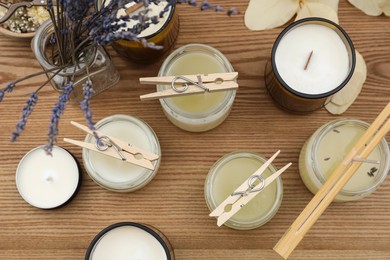 Photo of Glass jars with wax on wooden table, flat lay. Handmade candles