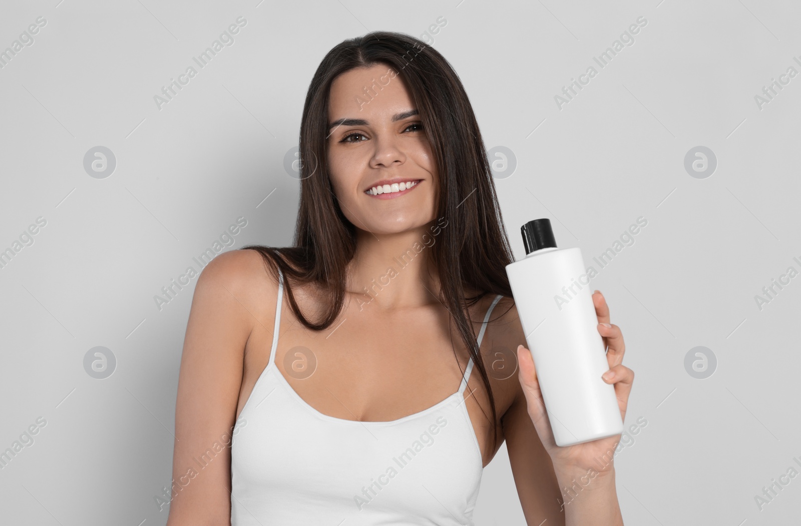 Photo of Beautiful young woman holding bottle of shampoo on white background