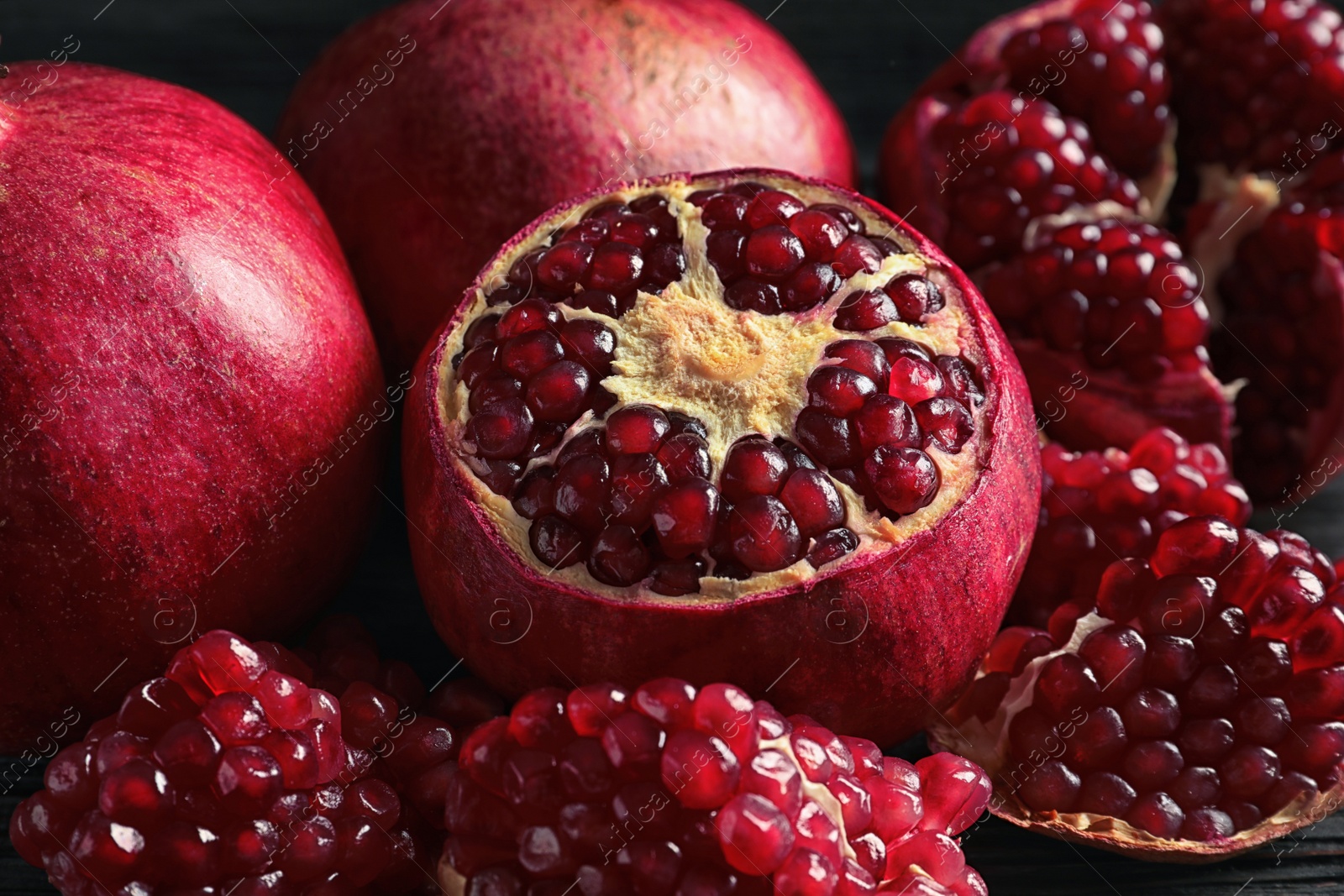 Photo of Ripe pomegranates and seeds on table, closeup view