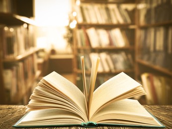 Open book on wooden table in library