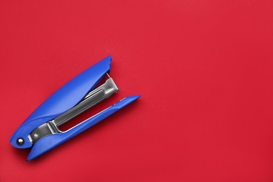 Photo of New bright stapler on red background, top view. Space for text