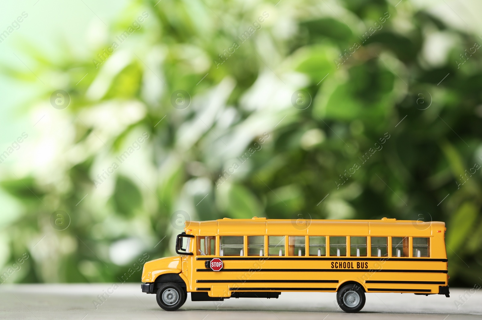 Photo of Yellow school bus on table against blurred background. Transport service