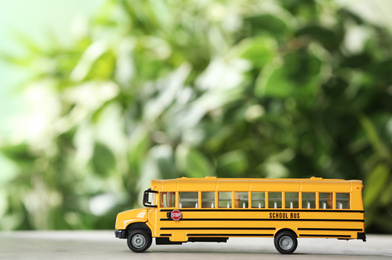 Photo of Yellow school bus on table against blurred background. Transport service