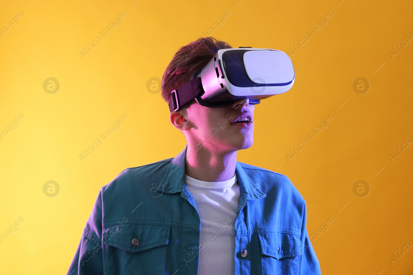 Photo of Young man with virtual reality headset on yellow background