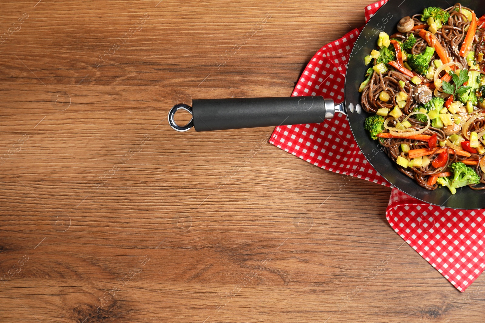 Photo of Stir-fry. Tasty noodles with meat and vegetables in wok on wooden table, top view. Space for text