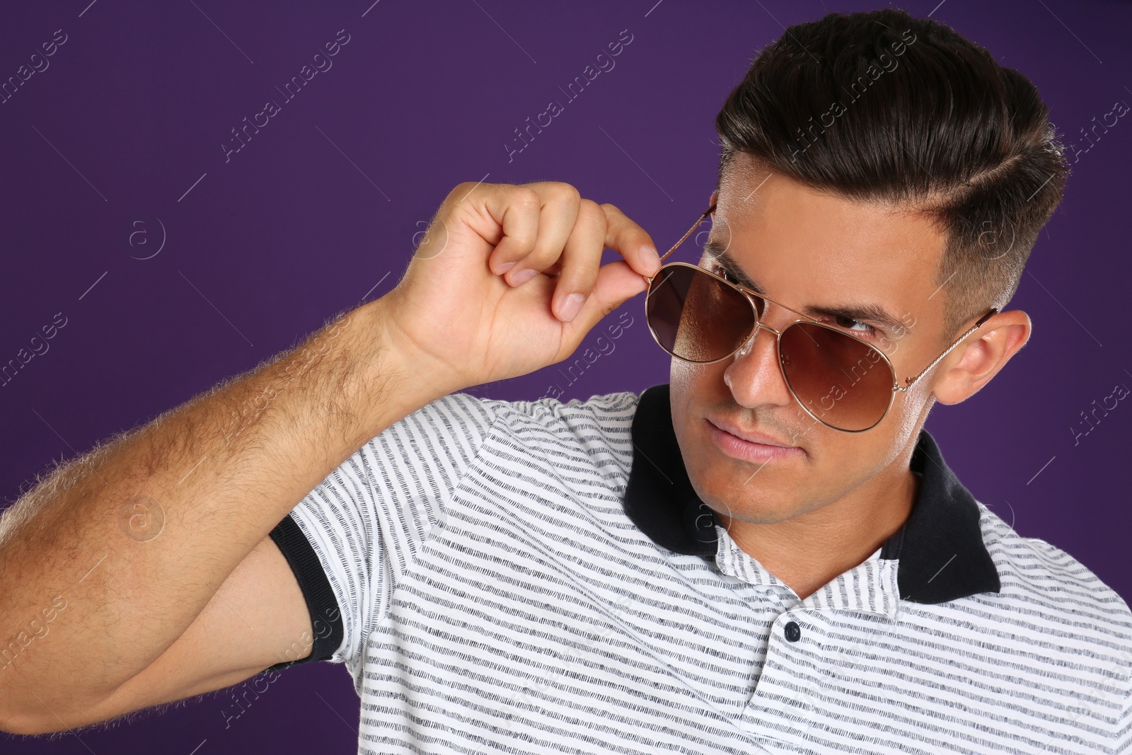 Photo of Handsome man wearing sunglasses on purple background