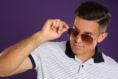 Photo of Handsome man wearing sunglasses on purple background